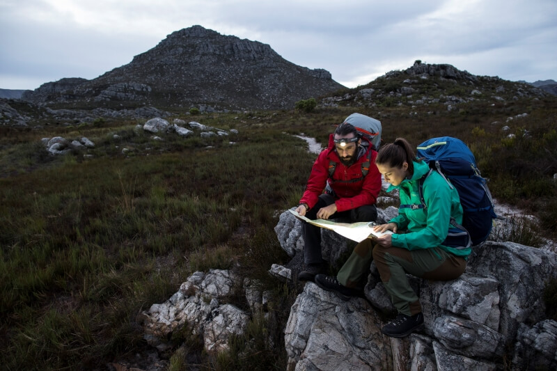 Das Bild zeigt zwei Bergsteiger, die mit Stirnlampen eine Karte lesen