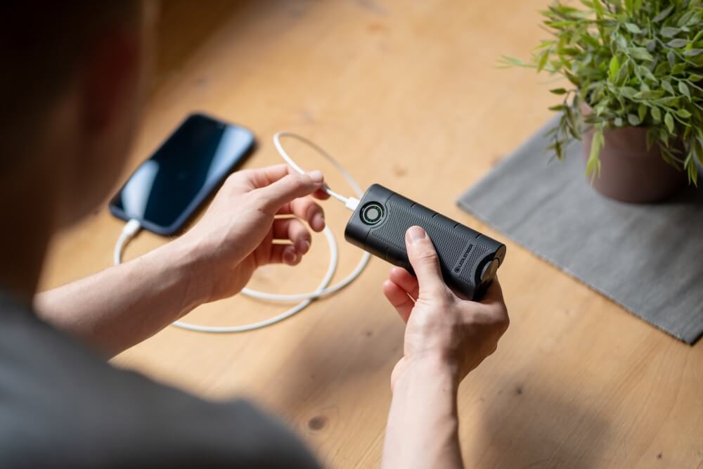 Jemand schließt sein Handy an eine Powerbank an